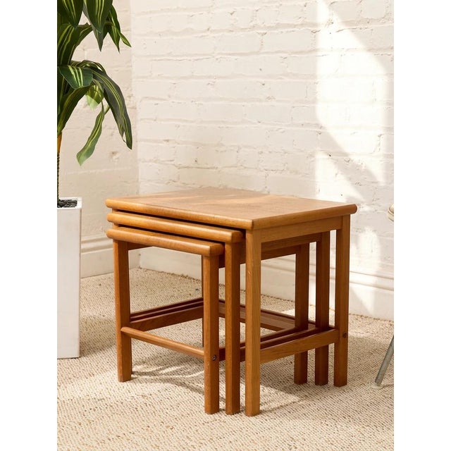 A handsome set of three vintage nesting tables featuring warm teak tones and a clean, space-saving design. Each table is...