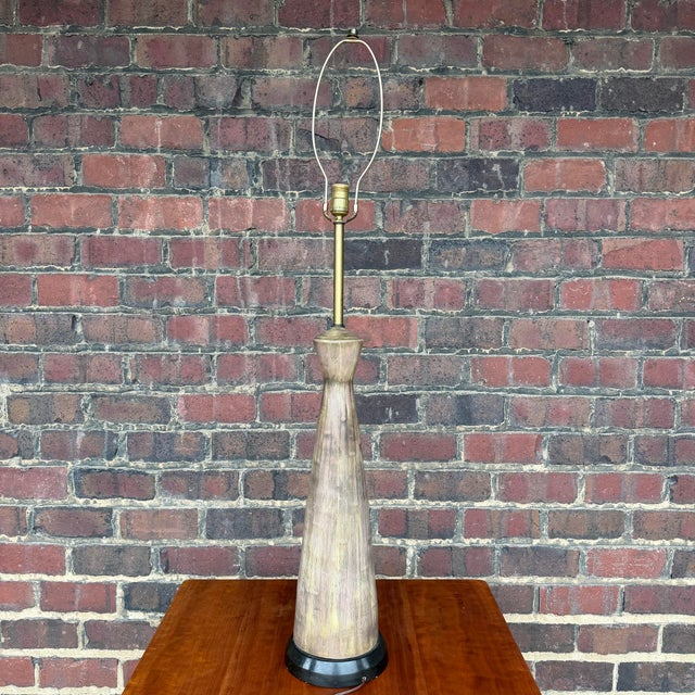 A lovely tall mid-century ceramic table lamp with a unique asymmetrical hourglass shape. The unique glaze has a light...