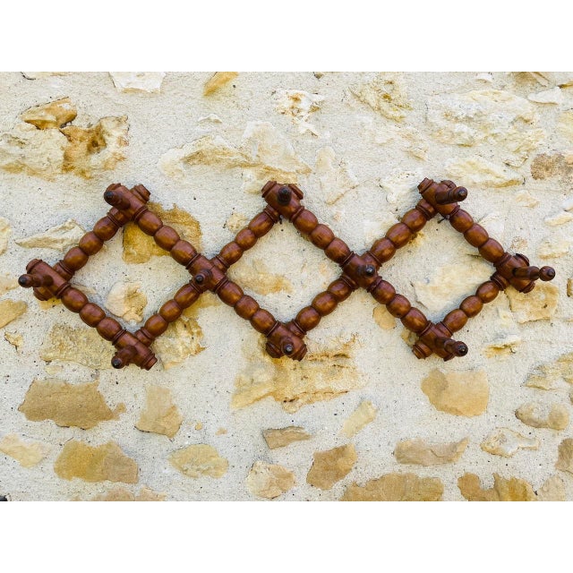 Vintage, french, wall-mount, folding/retractable/accordion coat rack. piece is made of beechwood, showcasing a...