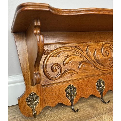 A beautifully crafted vintage French wall-mounted coat hanger, showcasing elegant carved detailing and a rich, warm oak...