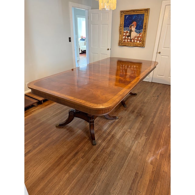 Substantial crotched mahogany dining table with banded inlay and double birdcage pedestals with brass endcaps. Table comes...