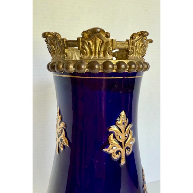 This lovely mid-20th-century European ceramic vase features a rich cobalt blue glazed finish accented with elegant gilt...
