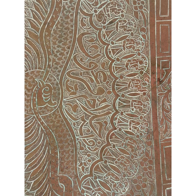 This large antique engraved copper tray is a striking example of Middle Eastern metalwork, featuring an intricately...