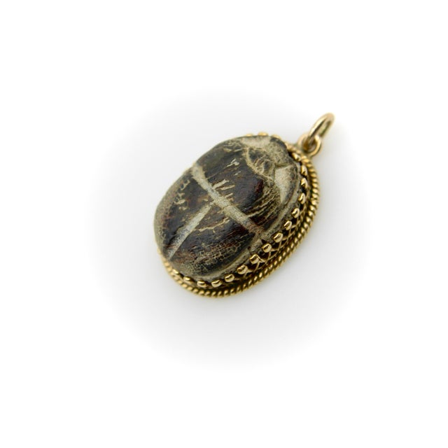 This beautiful Egyptian Revival pendant features a faience scarab beetle held in a 14k gold decorative Etruscan Revival...