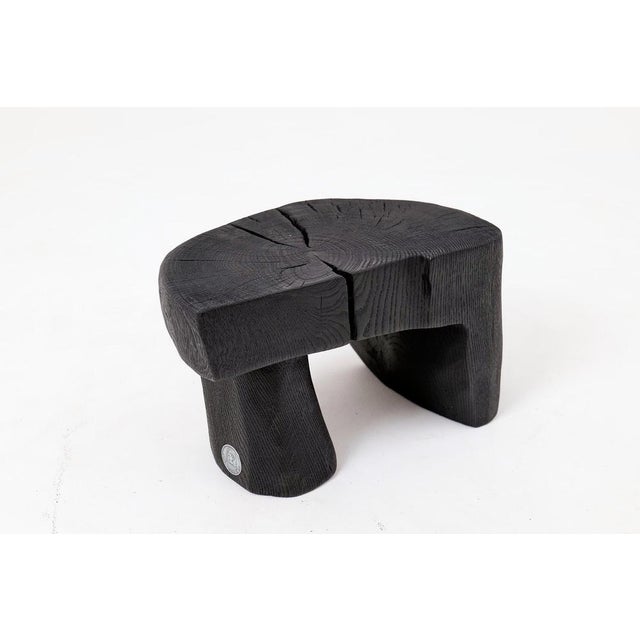 This striking functional sculpture is carved from a single piece of solid hardwood, ensuring a monolithic form with a...