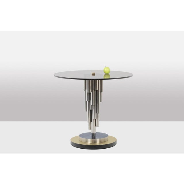 Organ-shaped pedestal table, in chrome metal and matte golden brass, with its smoked glass top. Work realized in the...