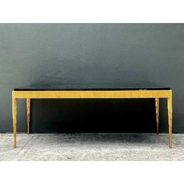 A vintage cocktail table crafted with a striking combination of a black stone top and a gilt brass base. The rectangular...