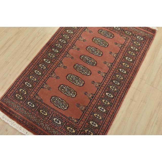 A tribal Bokhara rug hand-knotted with fine wool on a cotton foundation. This rug features a row of repeating medallions...