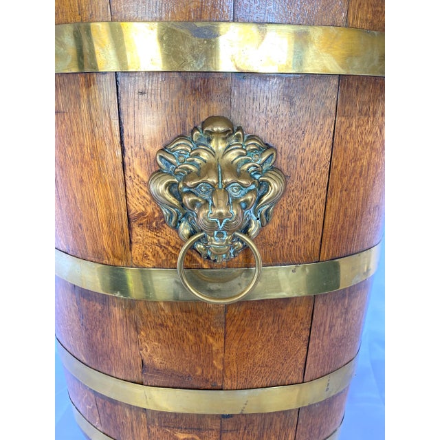 Late 1800s English oak artisan crafted barrel with thick brass bands, two handles and a lion's head medallion. Created...
