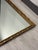 Striking vintage rectangular wall mirror featuring an ornate gilt frame with richly carved scrolling and floral detailing....