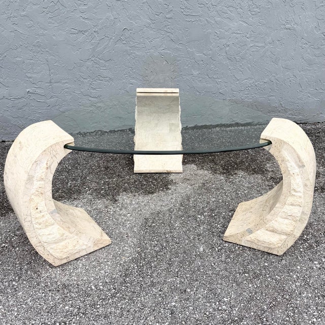 This postmodern coffee table balances sculptural stone with airy transparency. Three C-shaped tessellated stone supports...