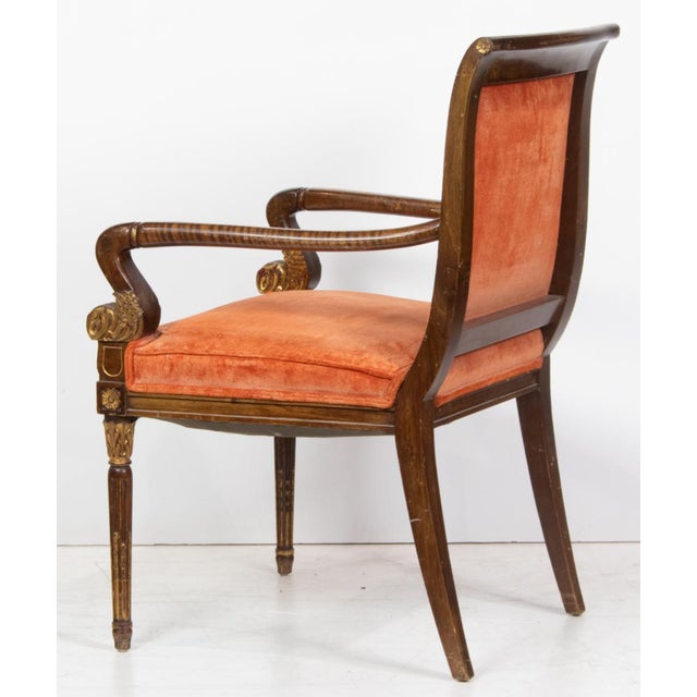 A Regency style parcel gilt armchair, the curved upholstered back with arms ending in leaf scroll, rising on fluted legs,...