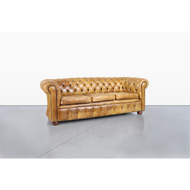 Envision transforming your living space with this remarkable vintage leather Chesterfield sofa, a true masterpiece of...
