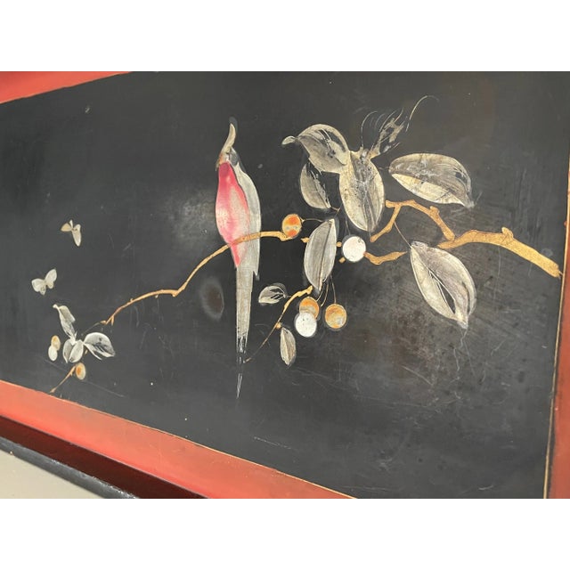 The vintage Chinoiserie black lacquered tray has been delicately painted depicting a single bird on branch surrounded by a...