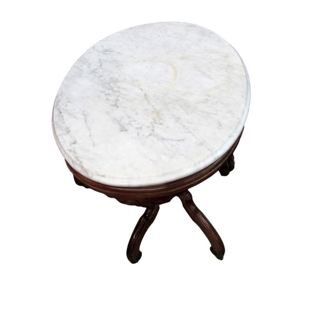 Beautiful antique Victorian-style marble top parlor table featuring an oval white marble top resting on an ornate dark...