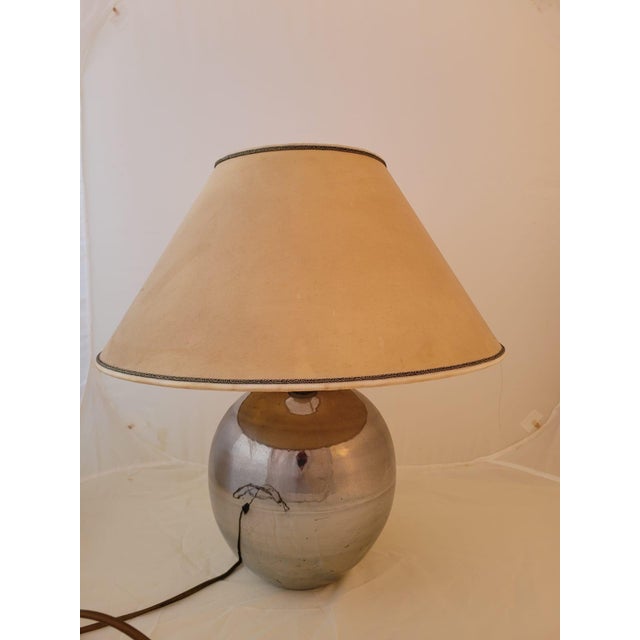 Vintage table lamp in a classic-decorative style with a glazed ceramic base with a silver finish, likely achieved with a...