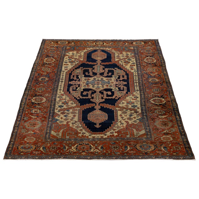 This exquisite antique hand-knotted Persian Serapi rug is a timeless testament to artisanal mastery. Set against a warm...