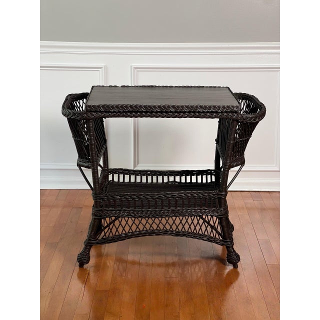 Antique Bar Harbor wicker table with side pockets and lower shelf in deep espresso brown, circa 1915. Unique table...