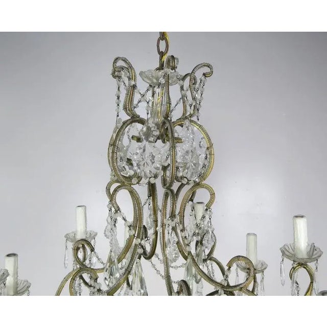 10-light French Louis XV style crystal beaded chandelier, circa 1930s. The chandelier is adorned with etched cut pendulum...