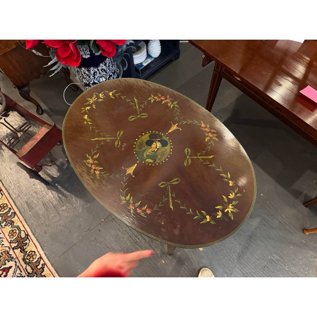 This is an antique adamesque style oval side table. It is beautifully hand painted with delicate floral garlands and a...