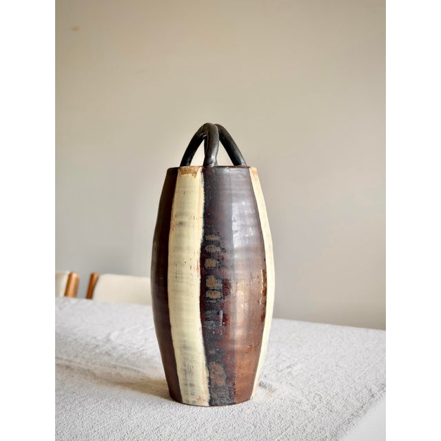 Mid-century studio pottery vessel, hand-thrown in stoneware with applied loop handles and a faceted body. The glaze is...
