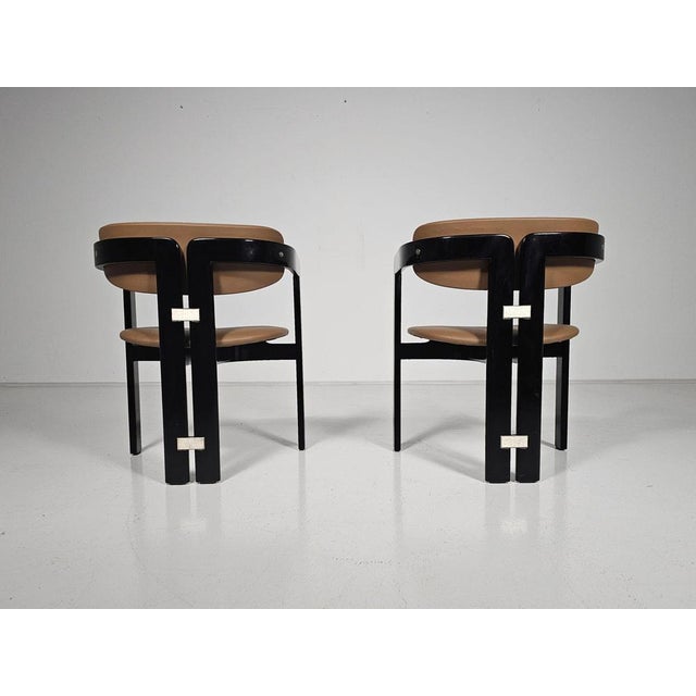 Augusto Savini for Pozzi, ‘Pamplona’ dining chairs, black lacquered ash wood, caramel leather upholstery, Italy, 1960s,...