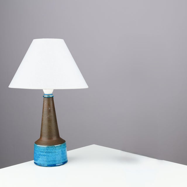 Table lamp made of partly blue-glazed stoneware with relief pattern. Signed “HAK" & "Denmark” on the bottom. Signature...