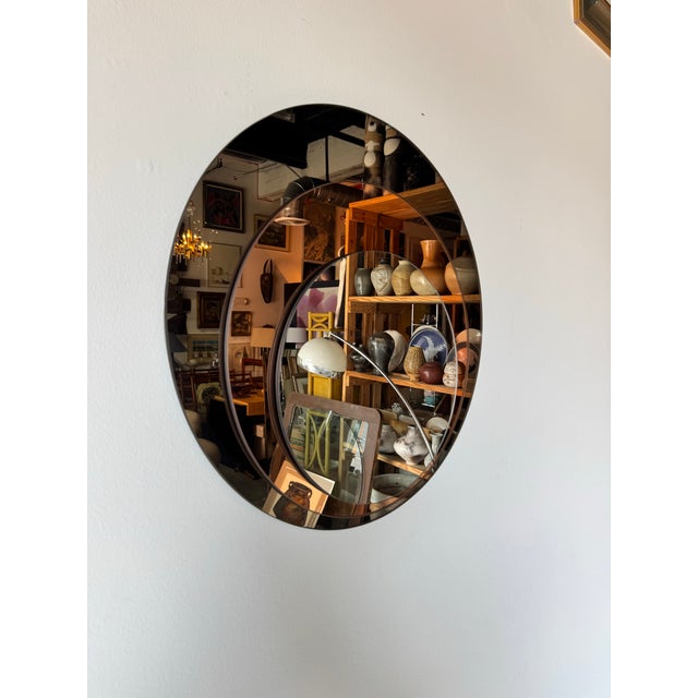 This striking 1980s Postmodern round wall mirror features a layered concentric design with tinted glass, creating a...
