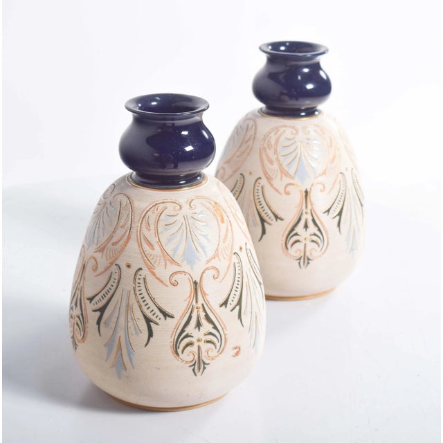 Pair of pottery cream-colored bulging vases, decorated with brownish designs and blurred shades of light blue. Dark blue...