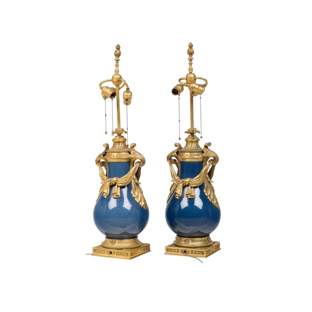 A striking pair of late 19th century French Louis XV style lamps, featuring Chinese porcelain bodies in a luminous robin’s...
