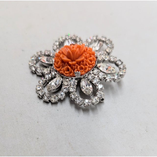 1950s rhodium plated round carved floral faux-coral with marquise and round clear rhinestones in loops surround brooch...