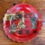 A single red lacquered papier mache wine coaster with a scalloped rim, decorated with a Japanese tea scene — figures in...