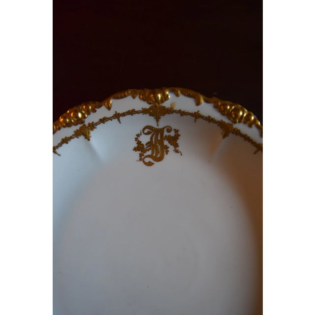 Lavish Belle-Époque Limoges porcelain charger with a deeply molded rocaille rim heavily gilded in raised gold and an inner...