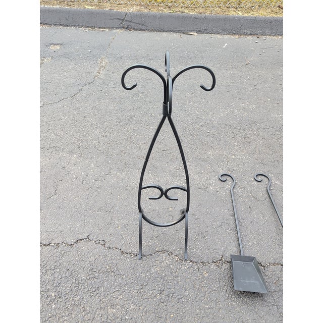 This vintage fireplace tool set consists of 4 fireplace tools made of black forged iron, including a stand