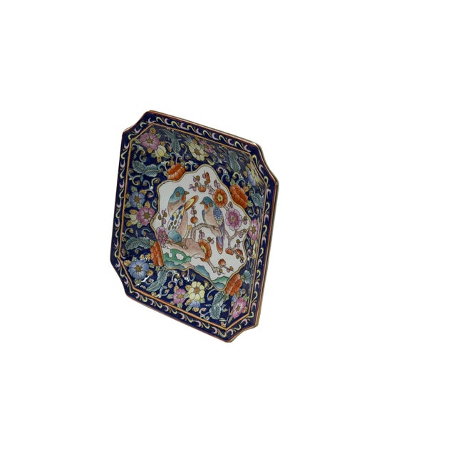 This finely detailed ceramic square tray features a rich, deep blue ground framing a central offwhite-toned cartouche....