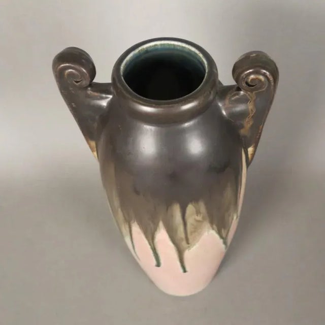 This glazed ceramic vase features a round handle and is signed on the underside. It is from around 1900 to 1920.