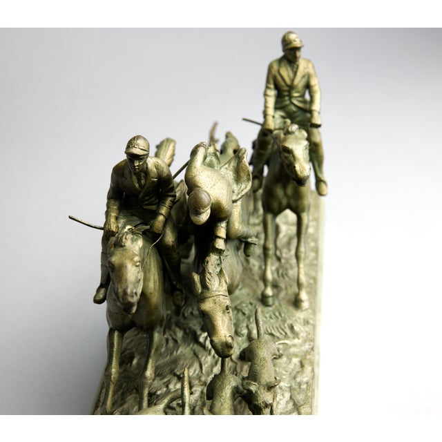 A dynamic Continental sculptural group depicting a fox hunt in full motion: two mounted riders in jockey caps atop...