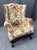 This early 1800s wingback armchair features an intricately carved wooden base with scrolled details, showcasing the...