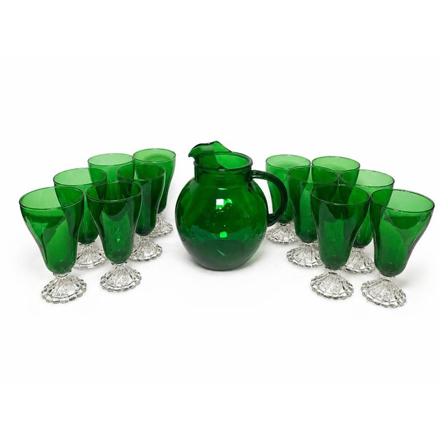 A striking 13-piece vintage Anchor Hocking glassware collection featuring one forest green “roly-poly” ball-shaped pitcher...