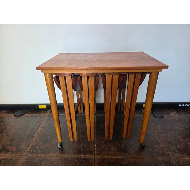 A 1960s set of teak round nesting tables. The Four folded tops pull out make round tables. They slide into a wooden track...