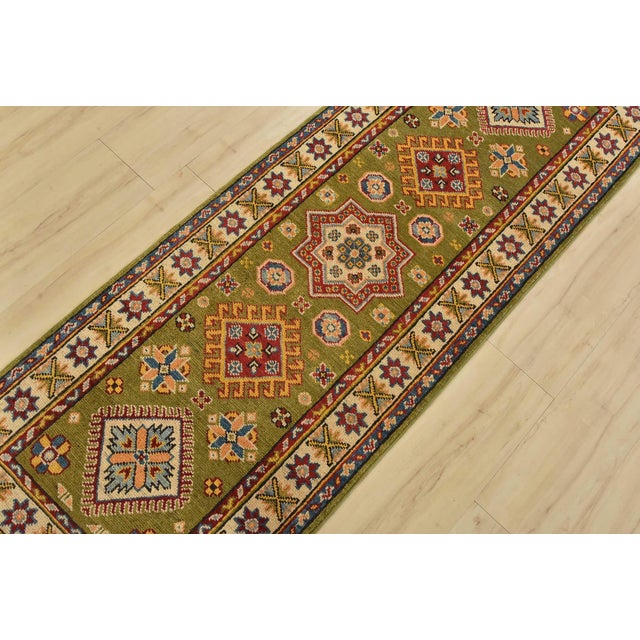 A tribal Caucasian Kazak runner hand-knotted with fine wool on a cotton foundation. This rug features a row of geometric...