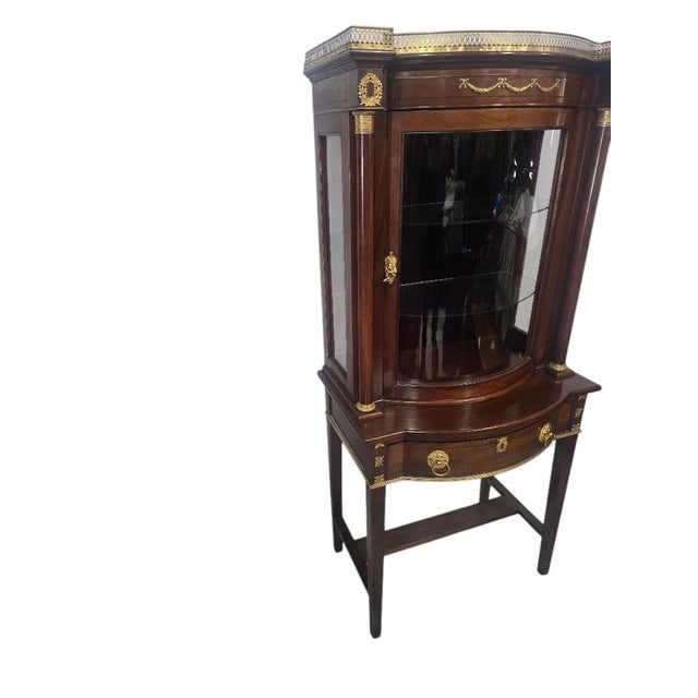A beautifully detailed vintage Federal style vitrine cabinet crafted in a rich mahogany finish with elegant brass-mounted...