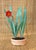 Carved Japanese potted flower. The "pot" is a natural material with small feet on the bottom. The red flower, possibly a...