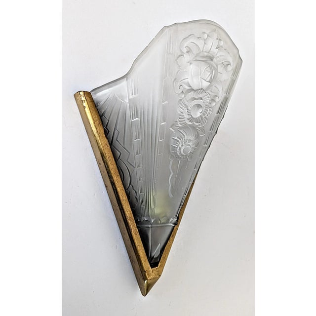 A single French Art Deco wall sconce in good condition. Molded clear frosted glass shade decorated with geometric and...