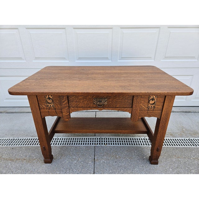 This wonderful Mission style oak desk has three drawers with copper colored hardware and a decorative carved apron. The...