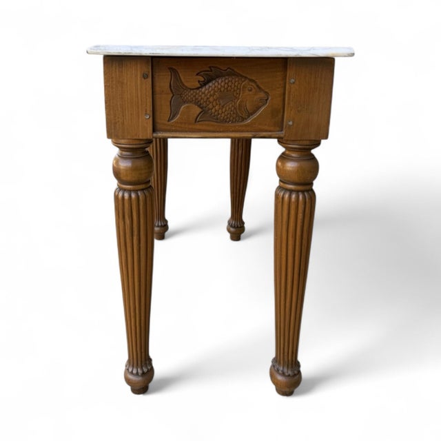 This is a late 20th century folk art inspired console table with Italian marble. The frieze is carved with a fish and...