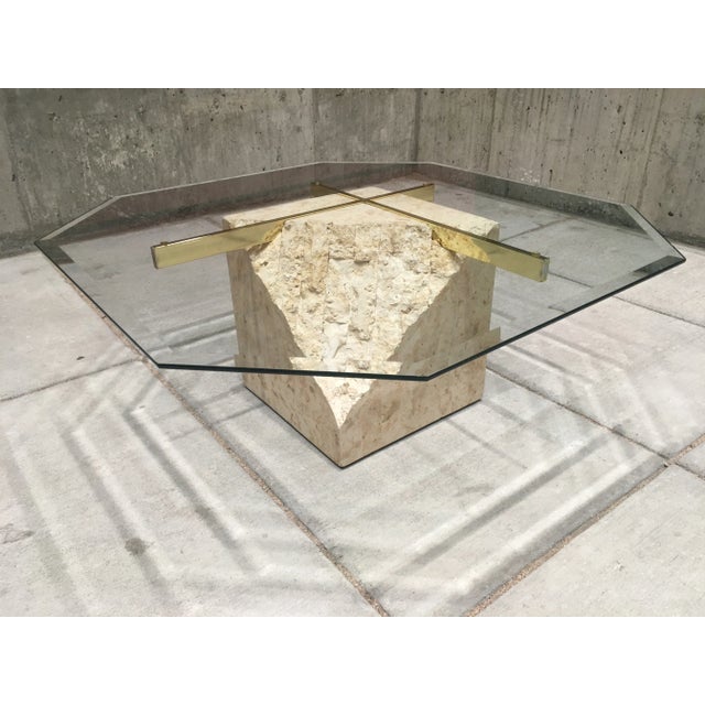 Vintage coffee table with beveled octagonal glass top, brass x-support, atop smooth polished and rough cut tessellated...