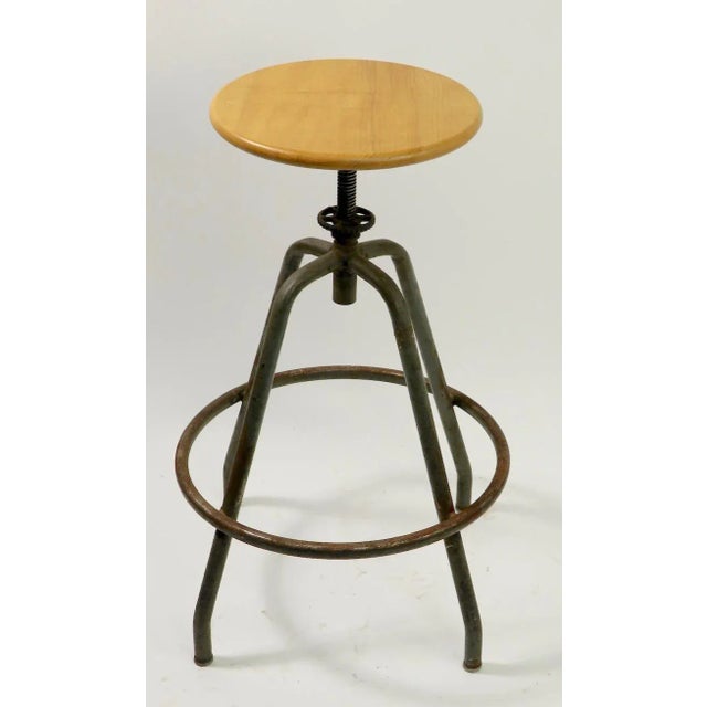 Classic industrial stool with solid wood disk seat, on four tubular steel legs. The seat swivels and is adjustable in...