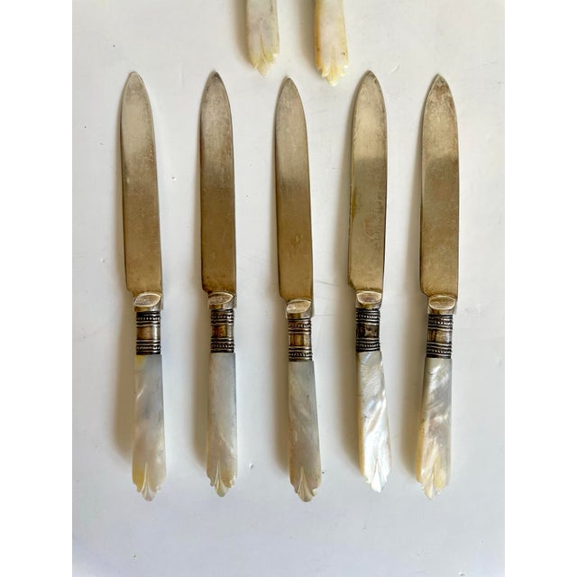 Dating to the late 19th century, this charming collection of seven antique table knives and spreaders features beautifully...