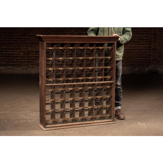 Early 20th century Wall-mounted oak mail sorter cabinet with numbered compartments, brass label holders, and glass front....
